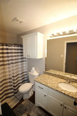 a bathroom with a granite countertop toilet sink and mirror