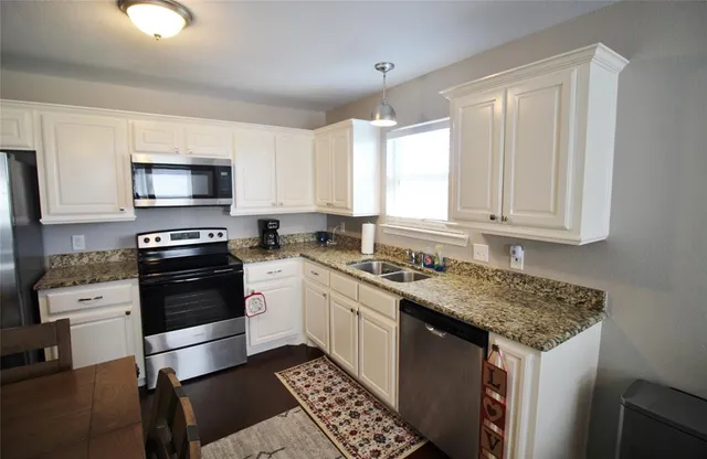 a kitchen with granite countertop a stove sink and cabinets