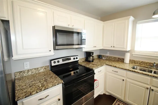 a kitchen with granite countertop white cabinets and appliances
