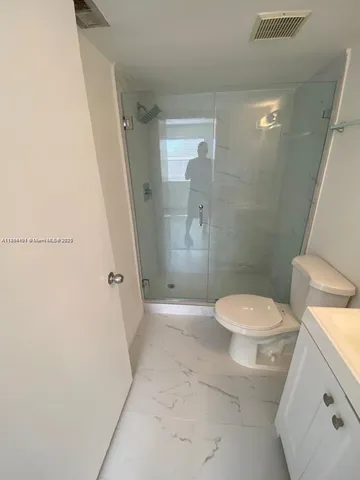 a bathroom with a granite countertop toilet a sink and shower