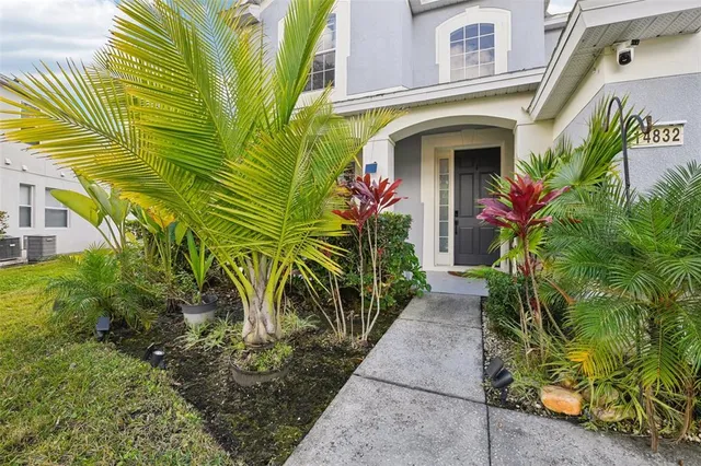 a front view of yellow house with plants