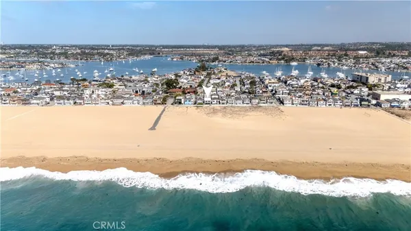 an aerial view of ocean and residential houses with outdoor space