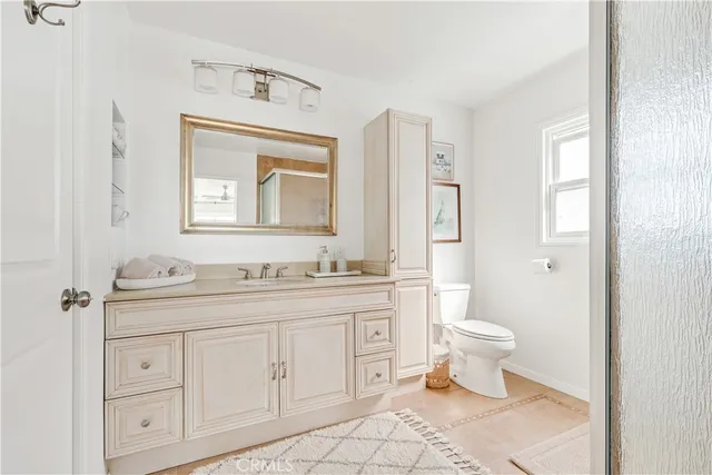 a bathroom with a toilet sink a mirror and vanity