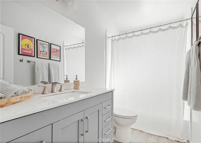 a bathroom with a granite countertop sink a toilet a shower and a mirror