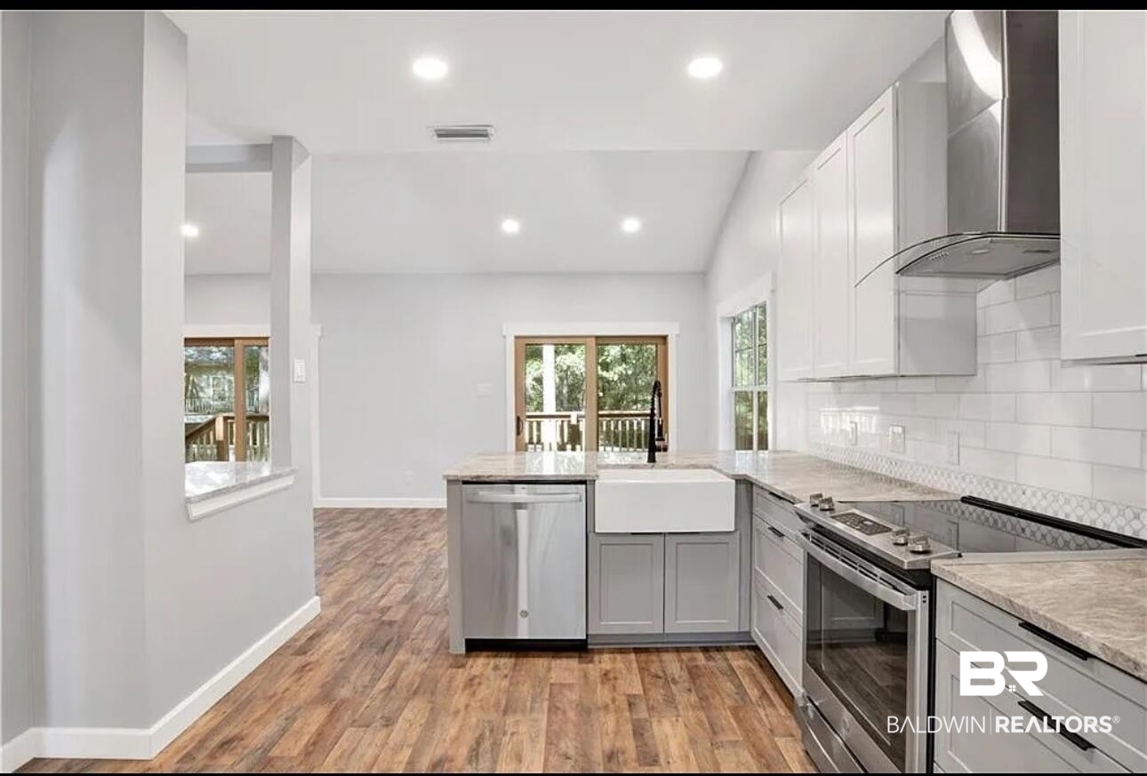 632 Ridgewood Drive Daphne, AL 36526 - Photo 7 of 36 Kitchen with appliances with stainless steel finishes, tasteful backsplash, sink, wall chimney range hood, and light hardwood / wood-style flooring