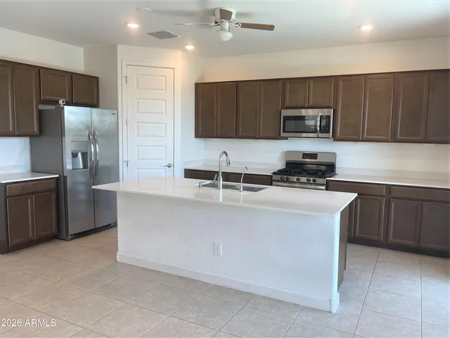 a kitchen with stainless steel appliances a sink a stove a microwave a refrigerator a sink and cabinets