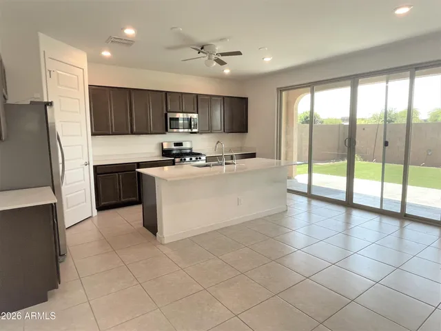 a kitchen with stainless steel appliances a sink a stove a refrigerator cabinets and a dining table