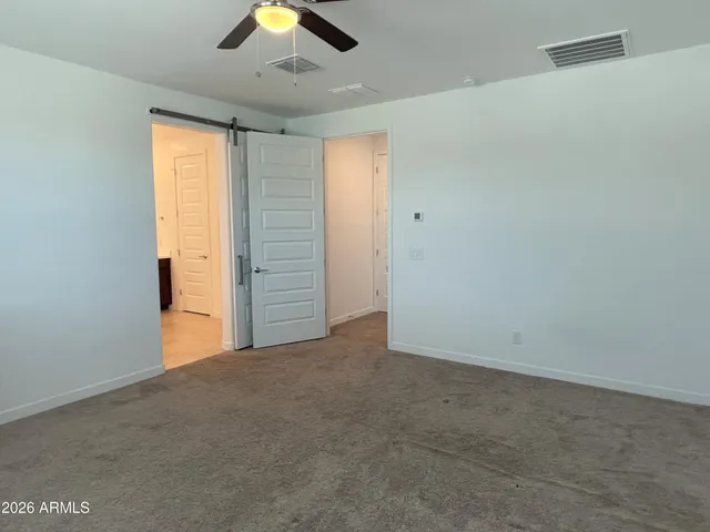 an empty room with closet and a ceiling fan