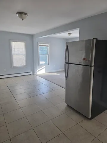 a view of a refrigerator in kitchen and an empty room