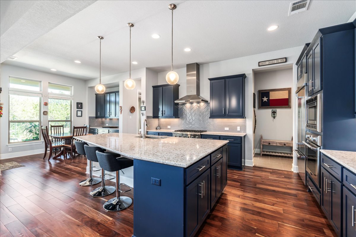 413 Montalcino Lane Georgetown, TX 78628 - Photo 15 of 40 a kitchen with kitchen island granite countertop a sink appliances and wooden floor