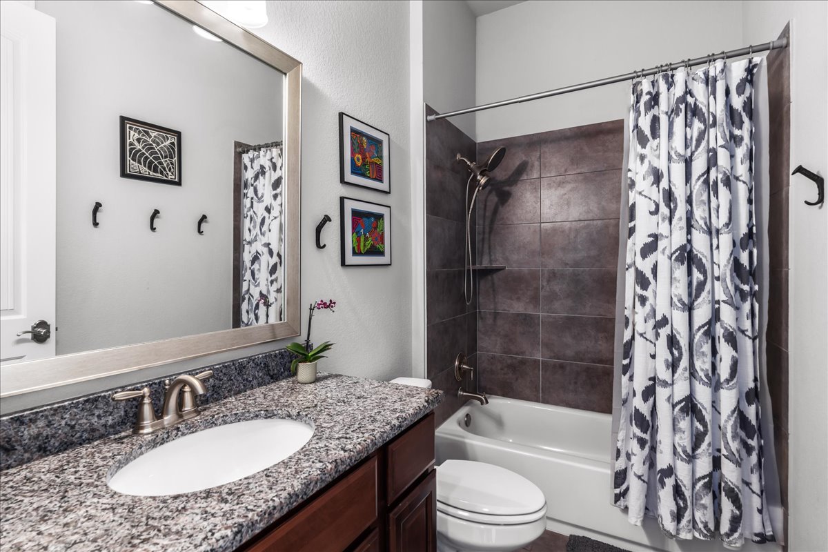 413 Montalcino Lane Georgetown, TX 78628 - Photo 10 of 40 a bathroom with a granite countertop sink toilet a shower curtain and a bath tub