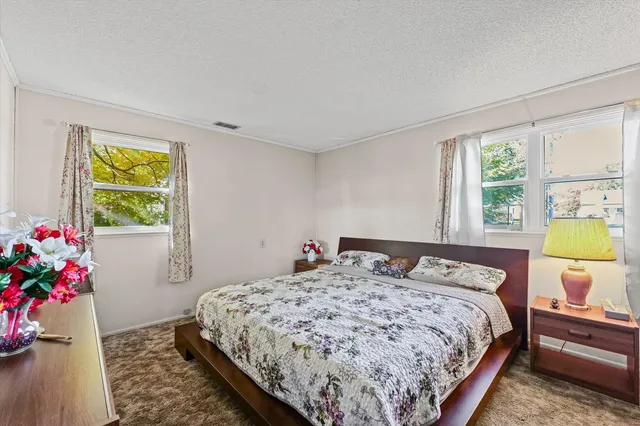 a bedroom with a bed and dresser with wooden floor