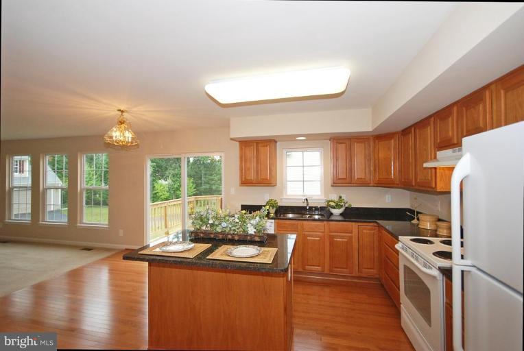 5946 Florey Road Hanover, MD 21076 - Photo 17 of 27 a kitchen with stainless steel appliances granite countertop a refrigerator a sink dishwasher a stove and white countertops with wooden floor