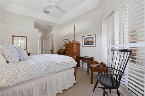 a bedroom with a bed a desk and chair with wooden floor