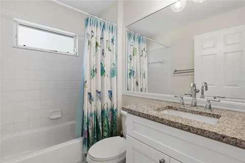 a bathroom with a granite countertop sink a toilet and shower