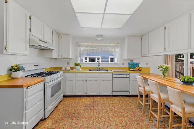 a large kitchen with a lot of white cabinets and stainless steel appliances