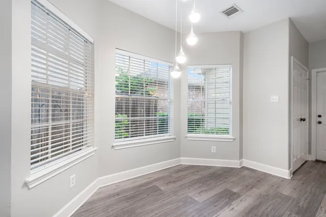 a view of an empty room with wooden floor and windows