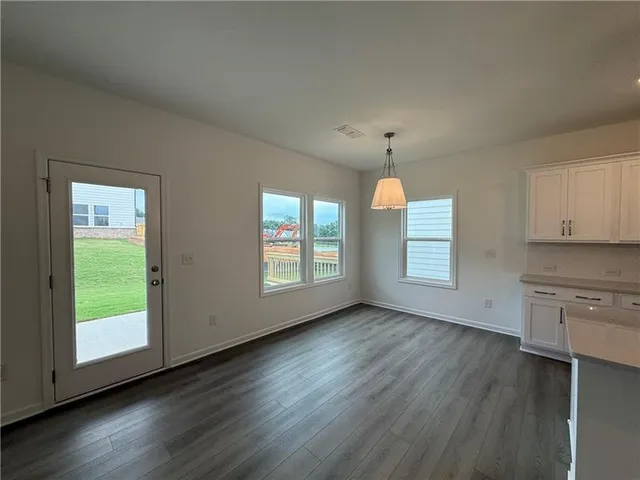 an empty room with wooden floors cabinet and windows