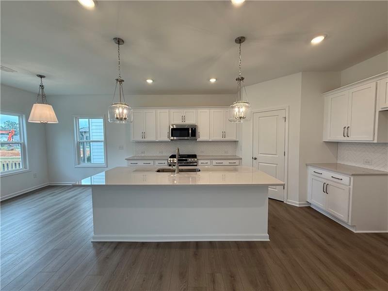 5449 Hargrove Way Flowery Branch, GA 30542 - Photo 14 of 39 a large kitchen with stainless steel appliances granite countertop a sink a stove and a wooden floor