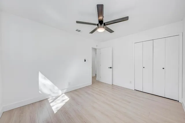 a view of empty room with wooden floor and ceiling fan