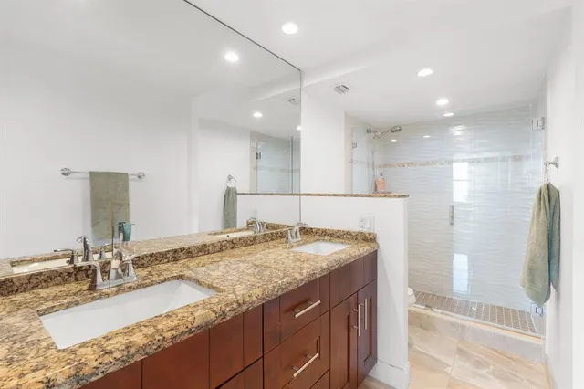 a bathroom with a granite countertop sink a shower and a mirror