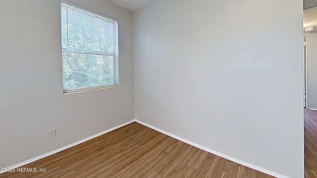 a view of an empty room with wooden floor and a window