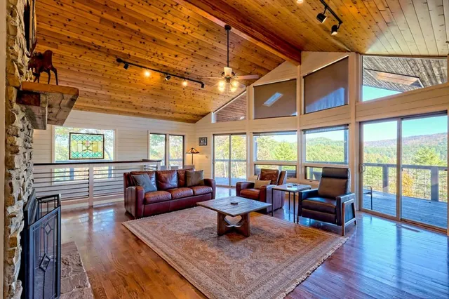 a living room with furniture large windows and wooden floor