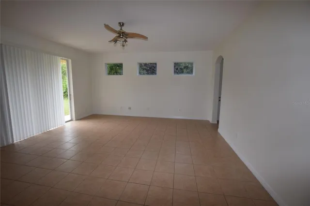 an empty room with a ceiling fan and windows