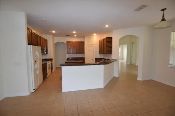 a view of kitchen with stainless steel appliances kitchen island granite countertop a refrigerator and a stove top oven