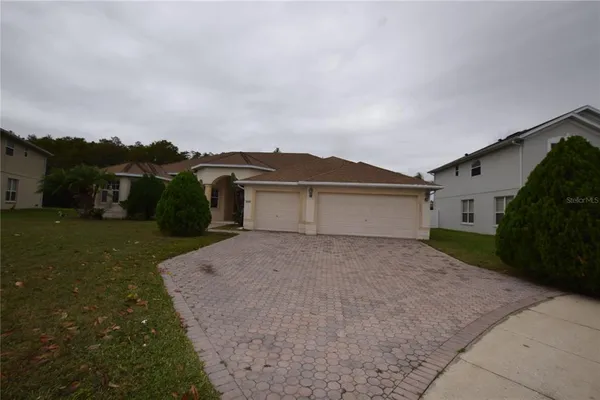 a view of house with a yard and a car parked in it