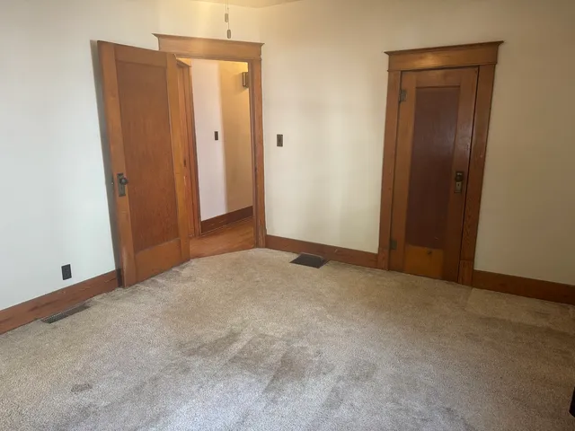 a view of an empty room with wooden floor and windows