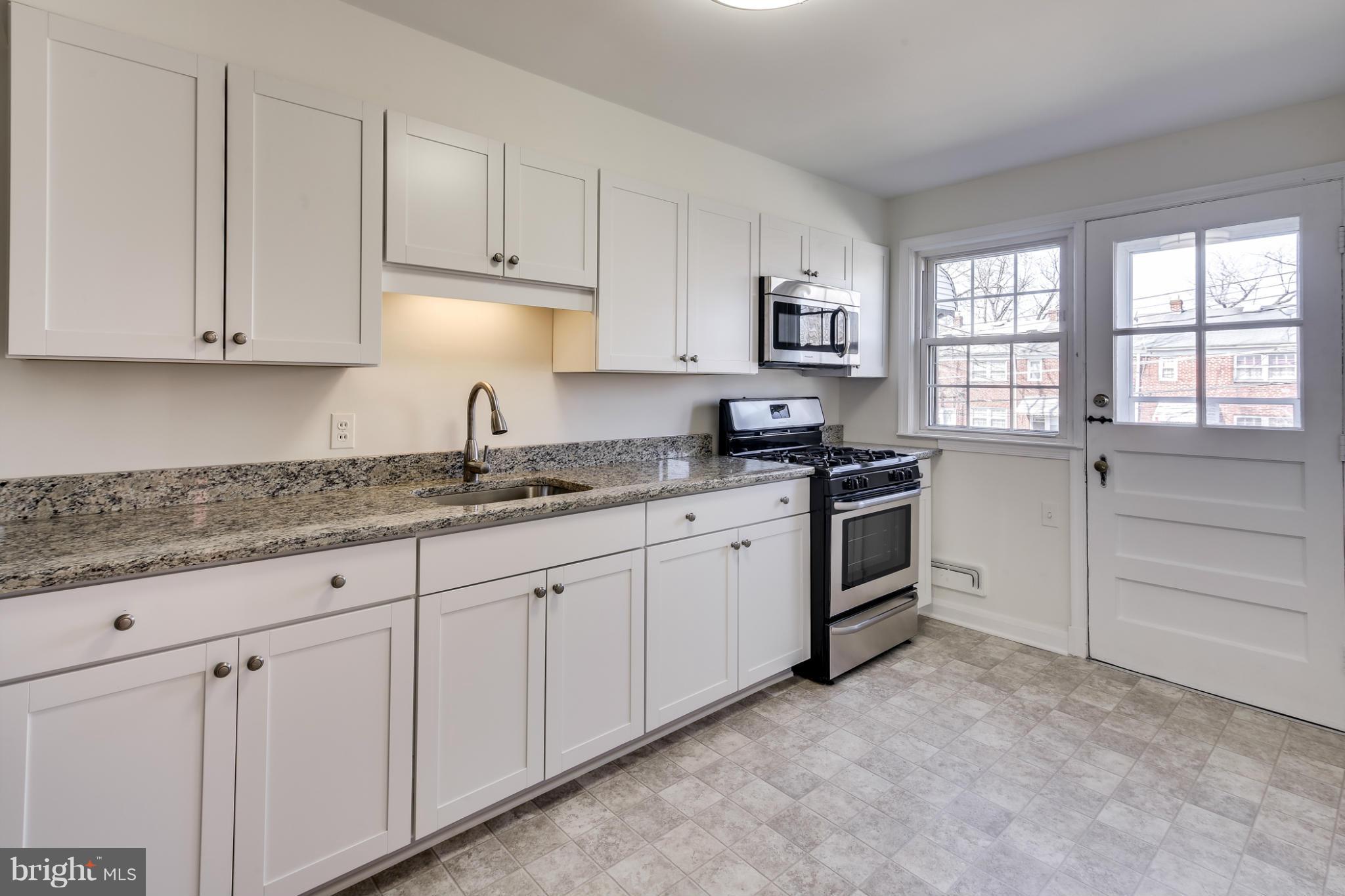 1512 Langford Road Baltimore, MD 21207 - Photo 9 of 30 a kitchen with granite countertop white cabinets and white appliances