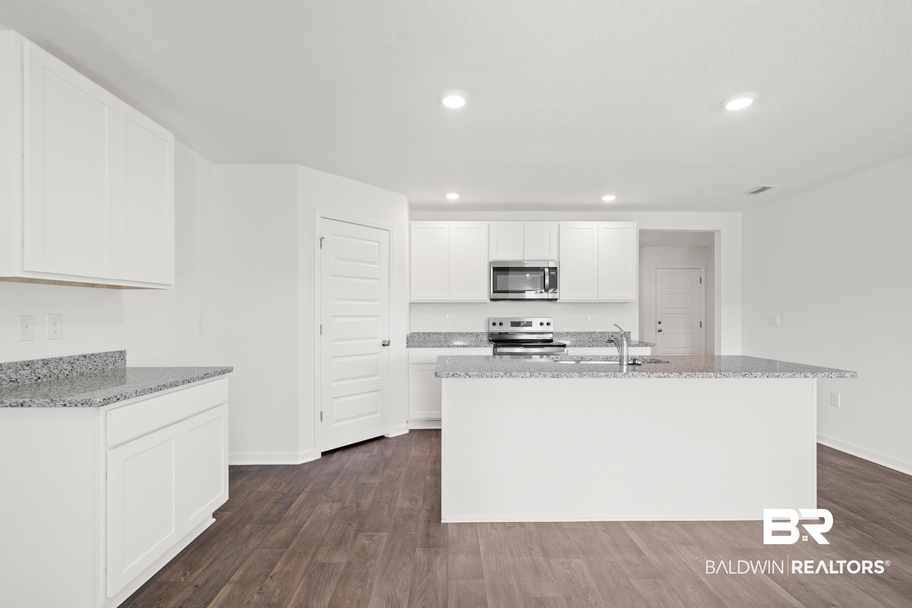 14615 Dayton Circle Foley, AL 36535 - Photo 15 of 27 Modern kitchen featuring white cabinetry, granite countertops, wood-finish flooring, recessed lighting, and stainless steel appliances including a microwave and range