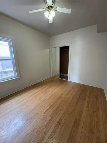 a view of empty room with wooden floor and fan