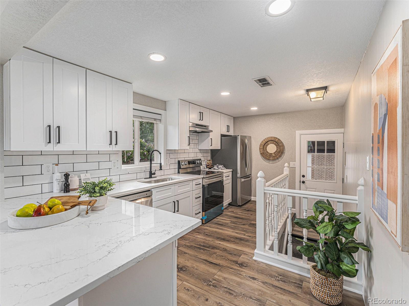 3895 Pierce Street Wheat Ridge, CO 80033 - Photo 2 of 33 a kitchen with stainless steel appliances granite countertop a sink a stove a refrigerator cabinets and living room view
