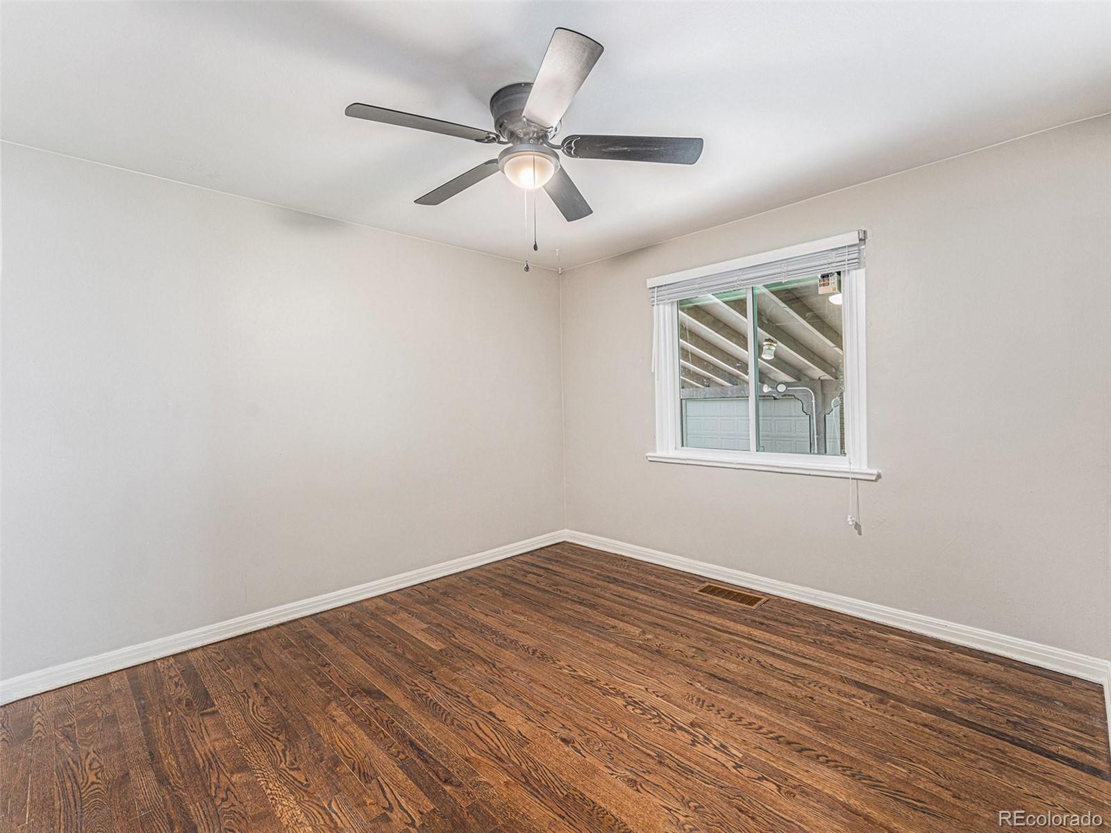 3895 Pierce Street Wheat Ridge, CO 80033 - Photo 22 of 33 an empty room with wooden floor ceiling fan and windows