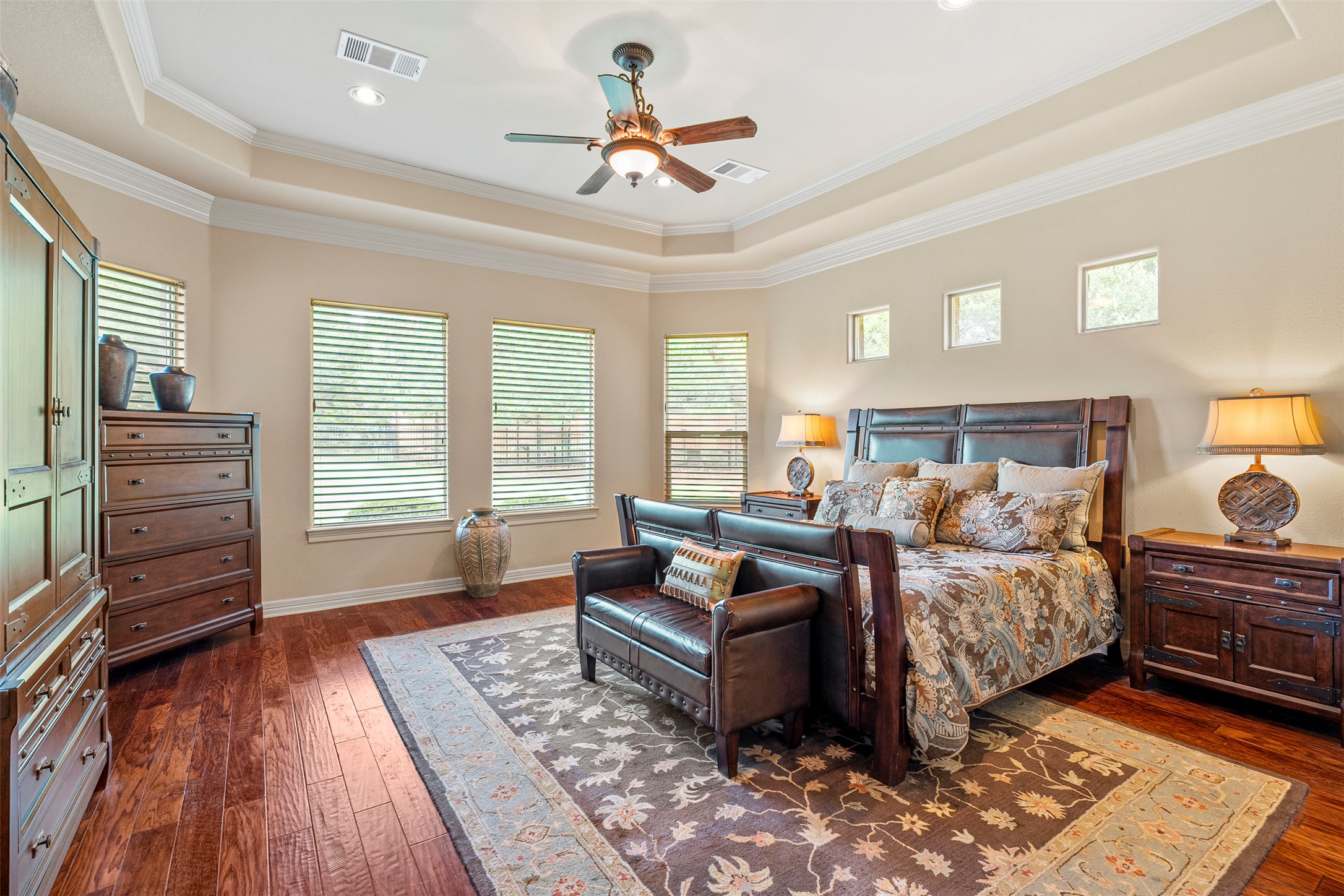 100 Portafino Lane Georgetown, TX 78633 - Photo 15 of 39 Bedroom with a tray ceiling, dark wood-style flooring, multiple windows, ornamental molding, and ceiling fan