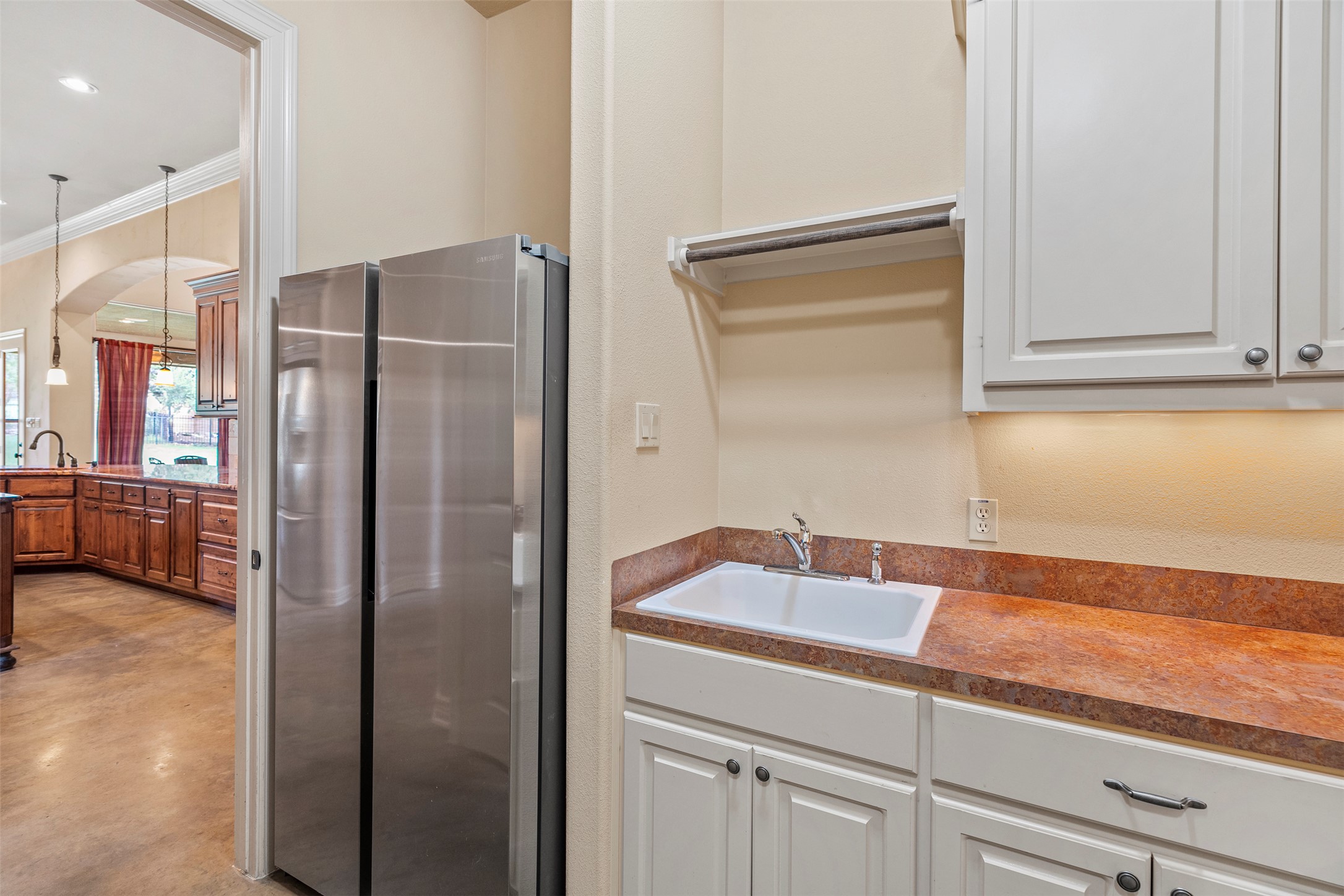 100 Portafino Lane Georgetown, TX 78633 - Photo 27 of 39 Kitchen featuring freestanding refrigerator, crown molding, finished concrete flooring, dark countertops, and decorative light fixtures