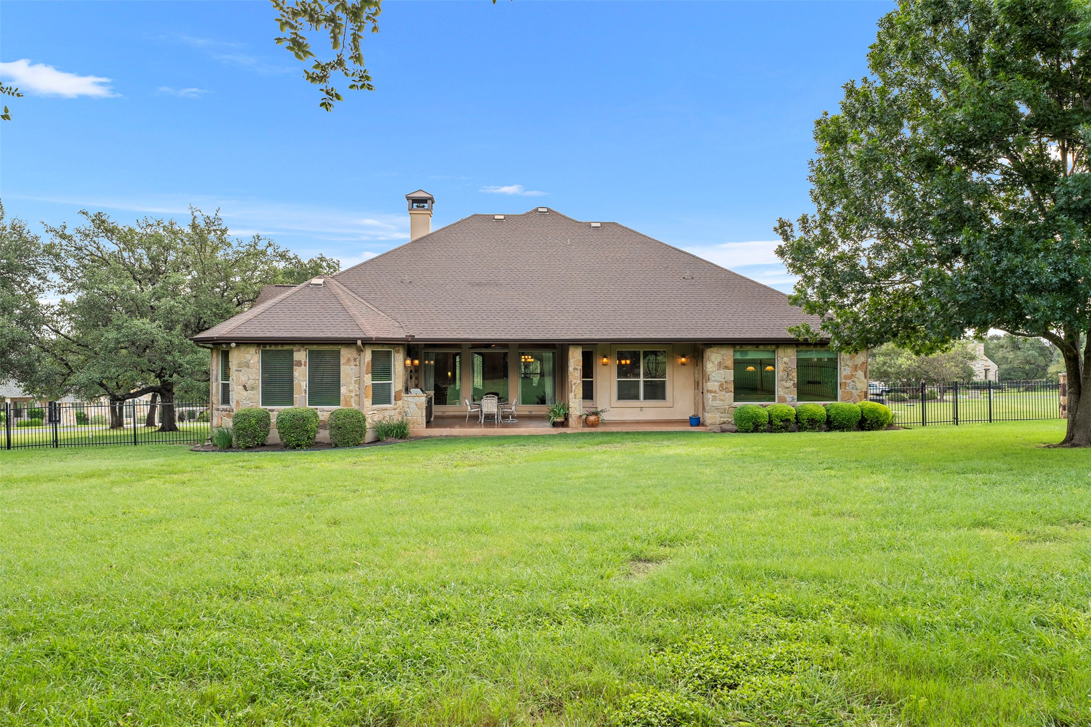 100 Portafino Lane Georgetown, TX 78633 - Photo 35 of 39 Rear view of house featuring stone siding, a chimney, a patio area, and a shingled roof