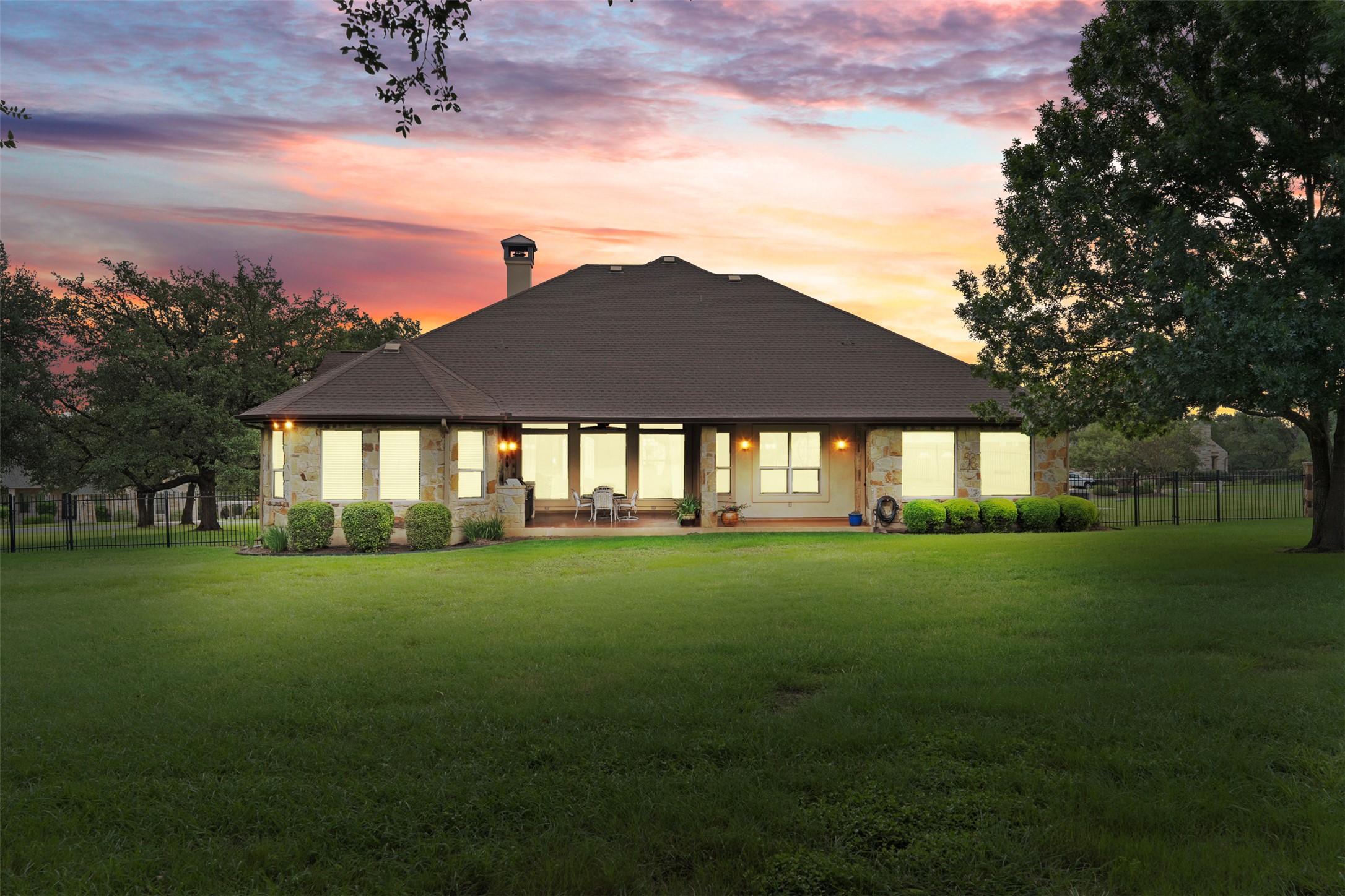 100 Portafino Lane Georgetown, TX 78633 - Photo 37 of 39 Back of house at dusk with stone siding, a patio area, and a chimney