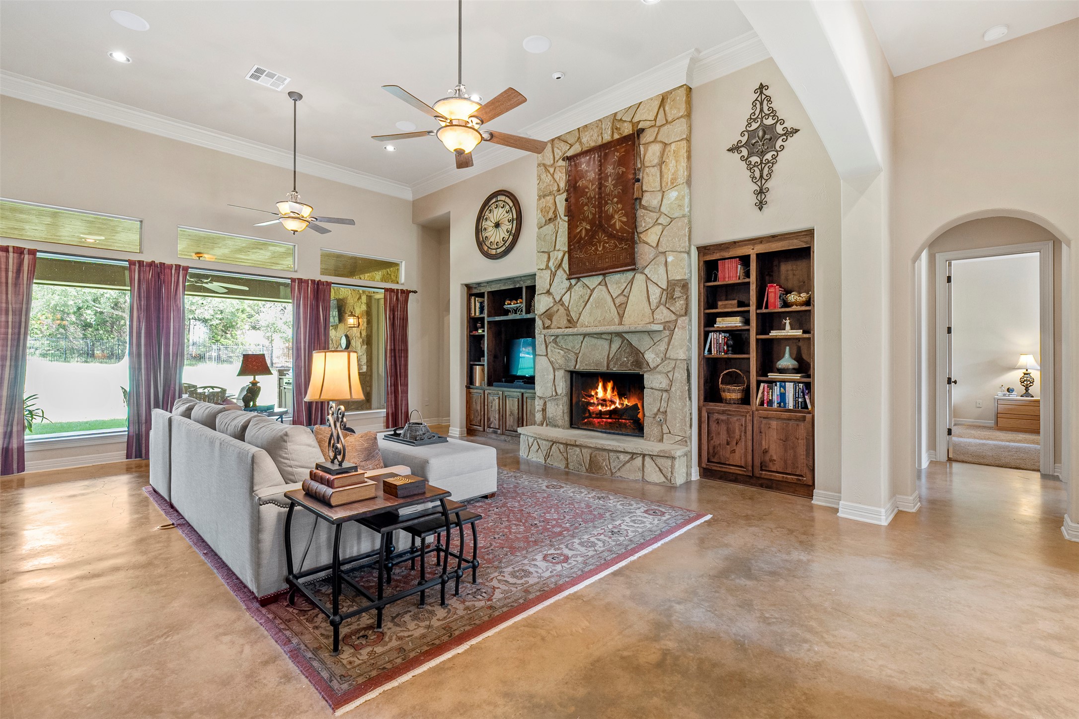 100 Portafino Lane Georgetown, TX 78633 - Photo 4 of 39 Living room featuring arched walkways, a ceiling fan, concrete floors, a high ceiling, and a fireplace