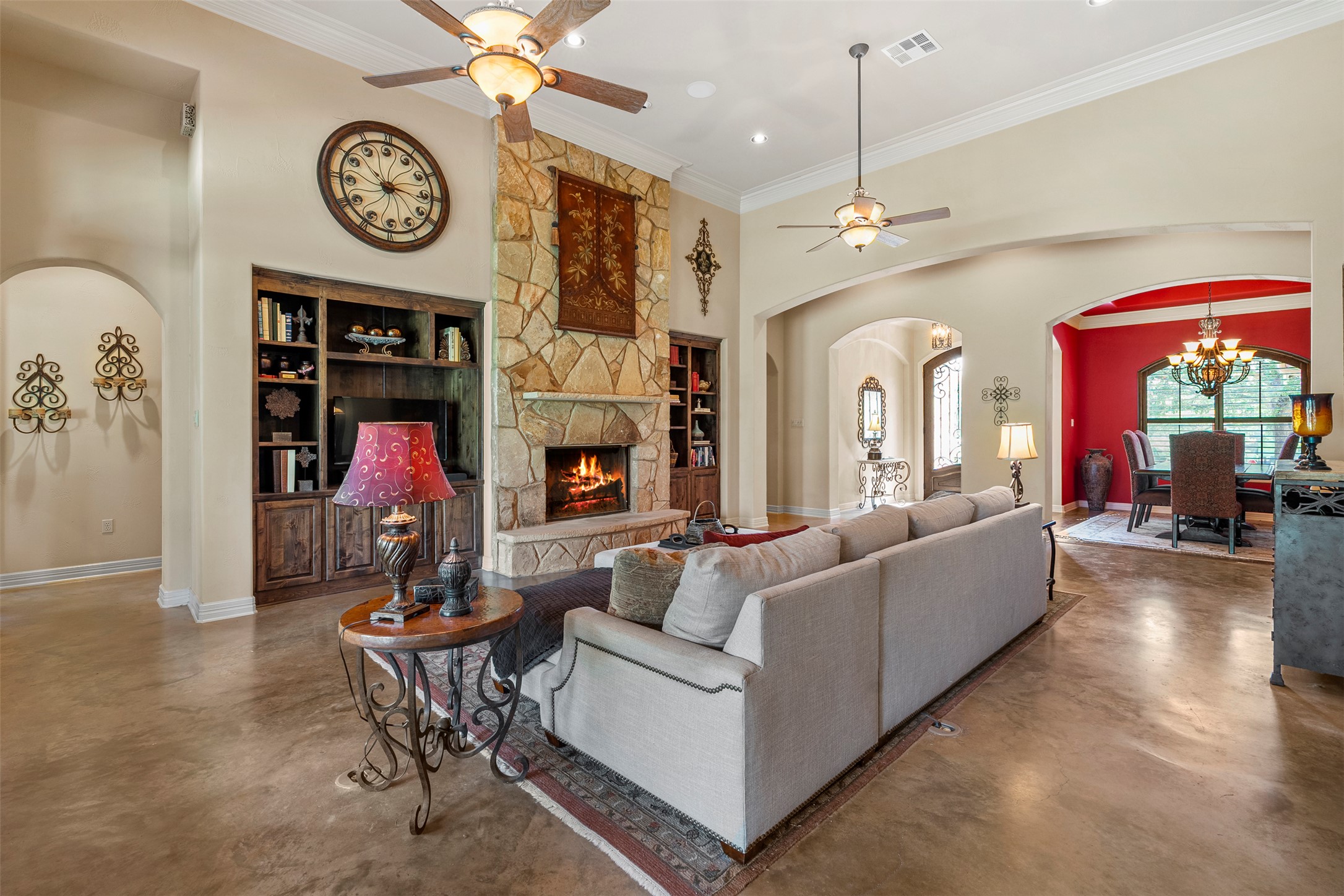 100 Portafino Lane Georgetown, TX 78633 - Photo 5 of 39 Living room featuring arched walkways, concrete floors, ceiling fan, a towering ceiling, and a fireplace