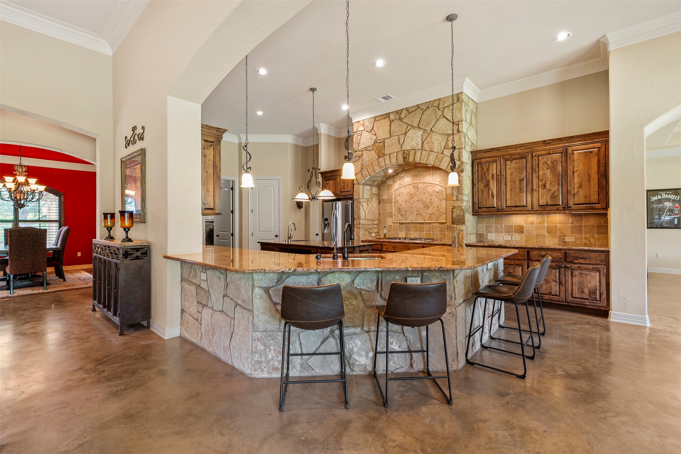 100 Portafino Lane Georgetown, TX 78633 - Photo 6 of 39 Kitchen with concrete flooring, backsplash, a kitchen bar, brown cabinets, and a chandelier