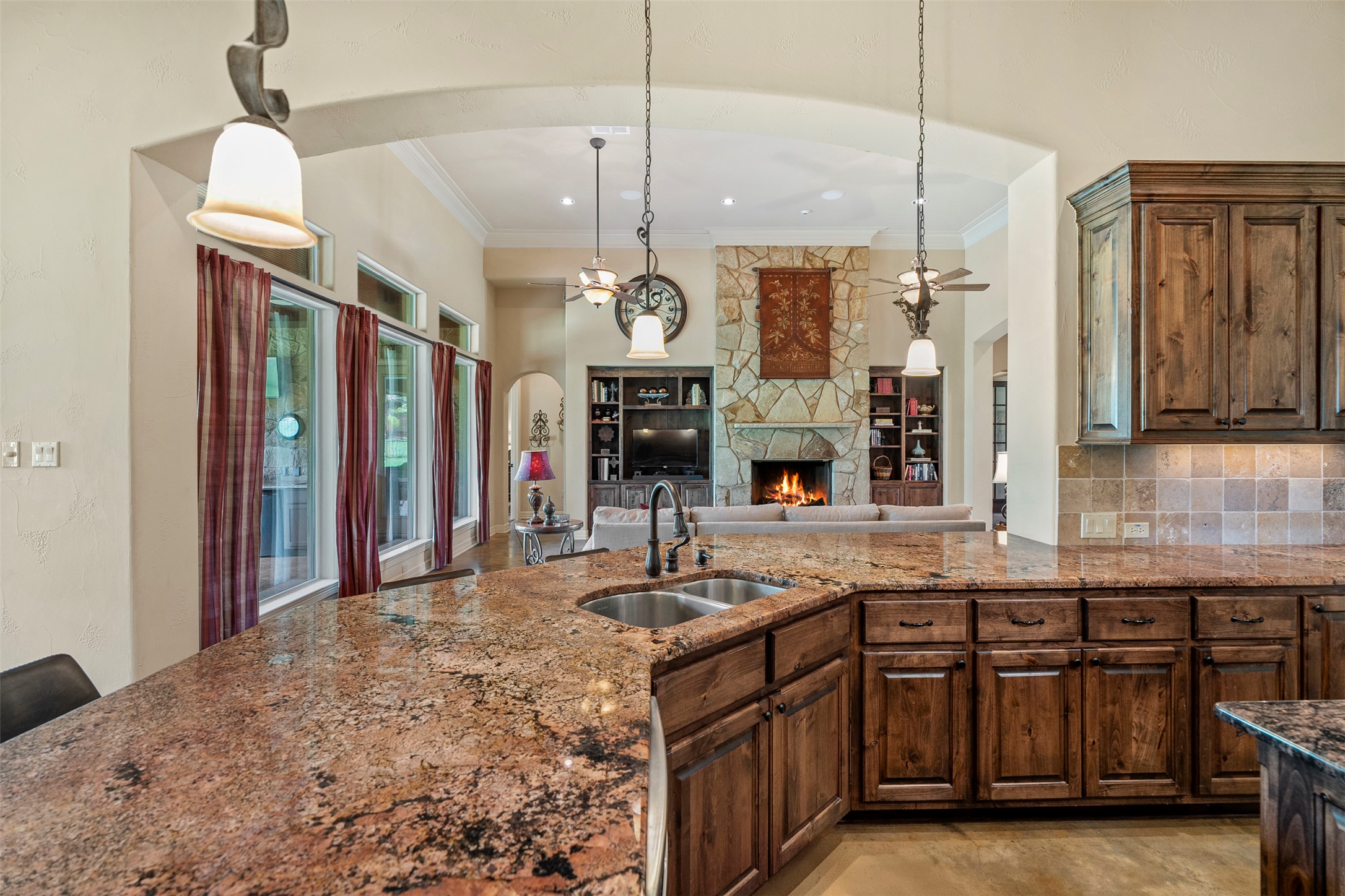 100 Portafino Lane Georgetown, TX 78633 - Photo 39 of 39 Kitchen with arched walkways, dark stone countertops, crown molding, open floor plan, and decorative light fixtures