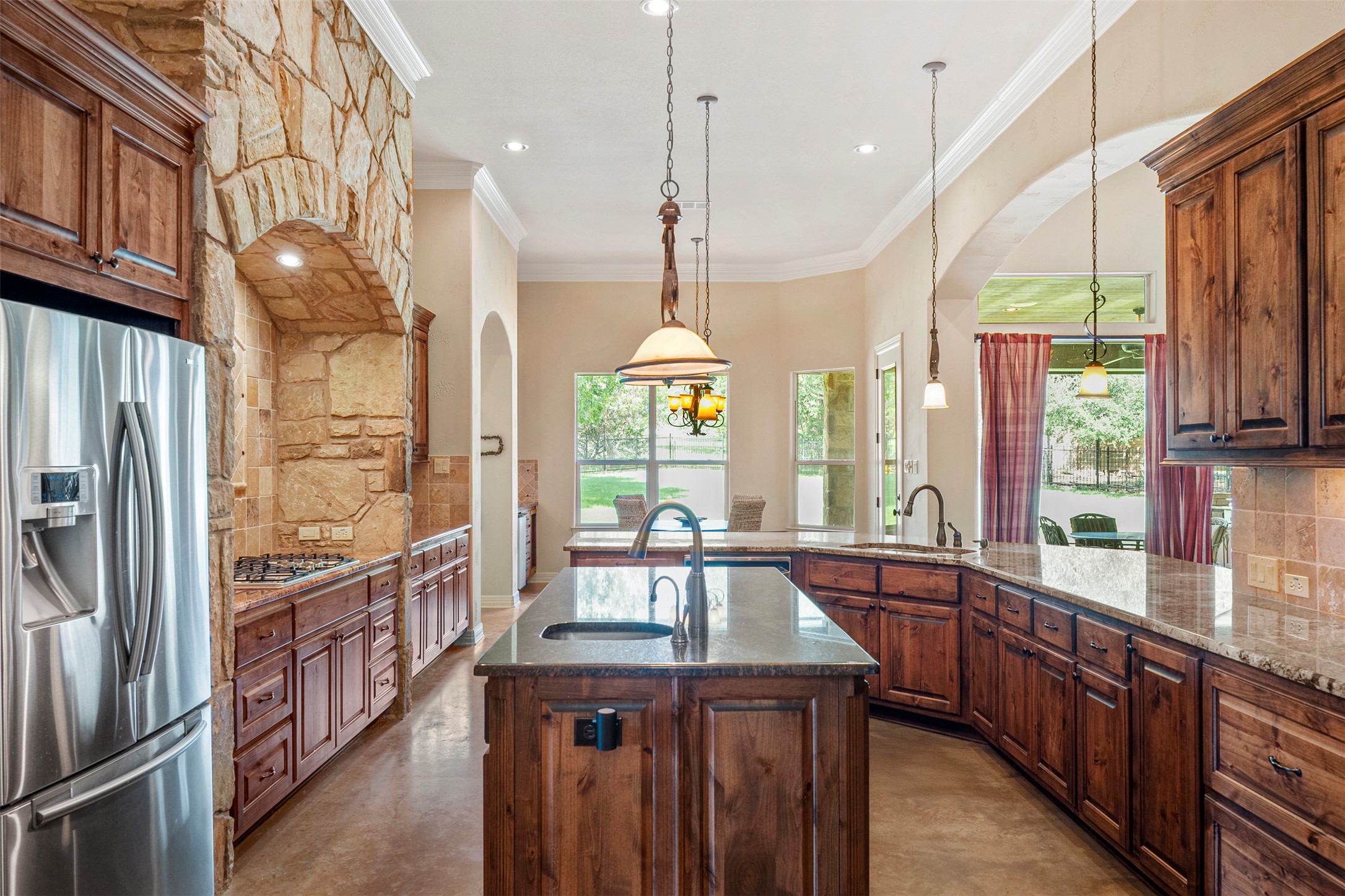 100 Portafino Lane Georgetown, TX 78633 - Photo 9 of 39 Kitchen featuring appliances with stainless steel finishes, finished concrete floors, tasteful backsplash, arched walkways, and dark stone counters