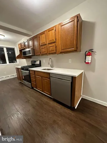 a kitchen with stainless steel appliances granite countertop a sink dishwasher stove top oven and cabinets with wooden floor