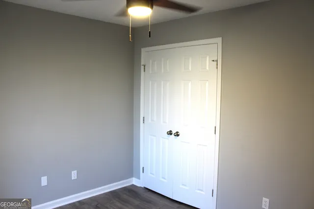 an empty room with wooden floor and fan