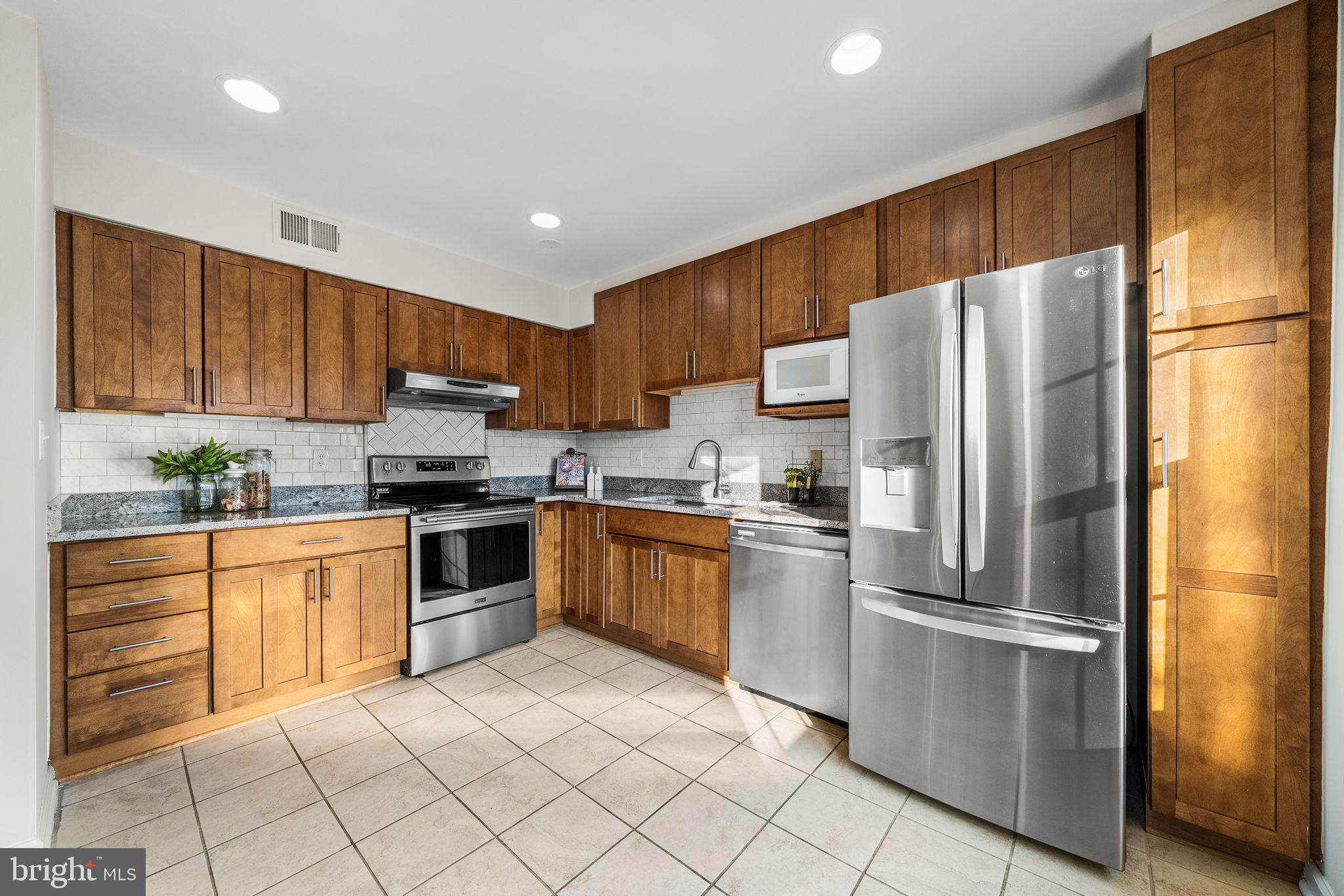 8333 Garfield Court Springfield, VA 22152 - Photo 18 of 60 a kitchen with granite countertop a refrigerator and a stove top oven