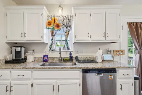 a kitchen with granite countertop white cabinets and stainless steel appliances