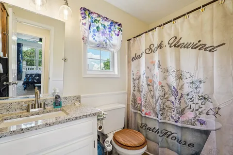 a bathroom with a granite countertop sink a toilet and a shower curtain